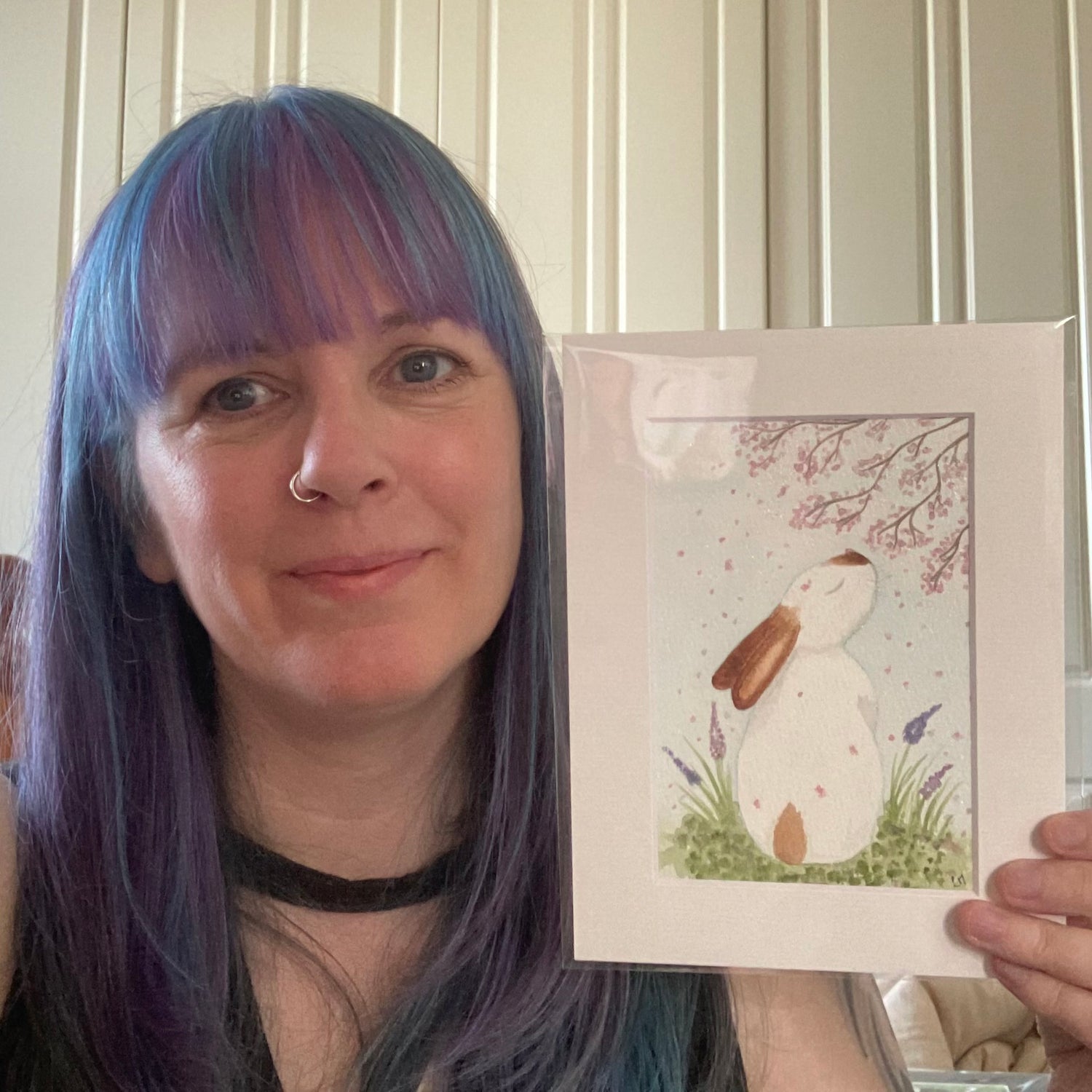 Me holding a painting with a rabbit illustration in front of a neutral background