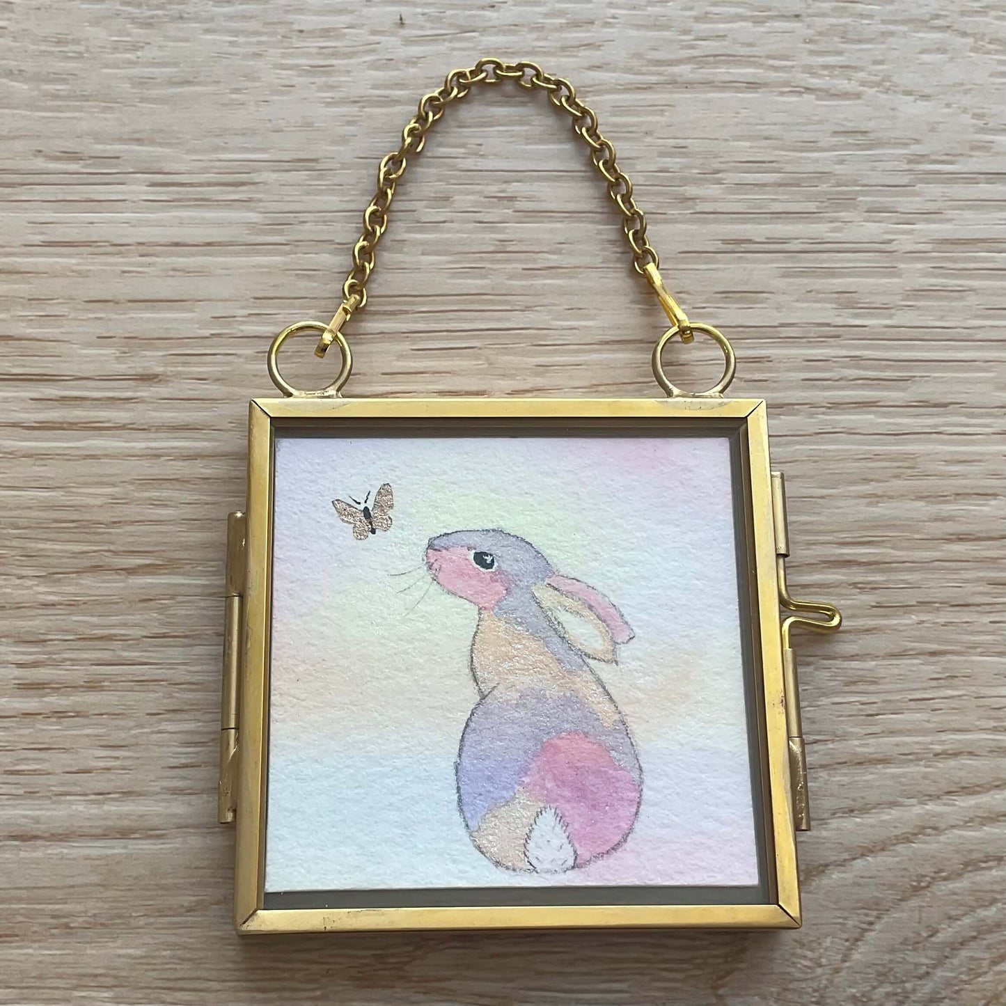 Original pastel rainbow bunny art decoration painting in a brass frame titled Rainbow of Hope