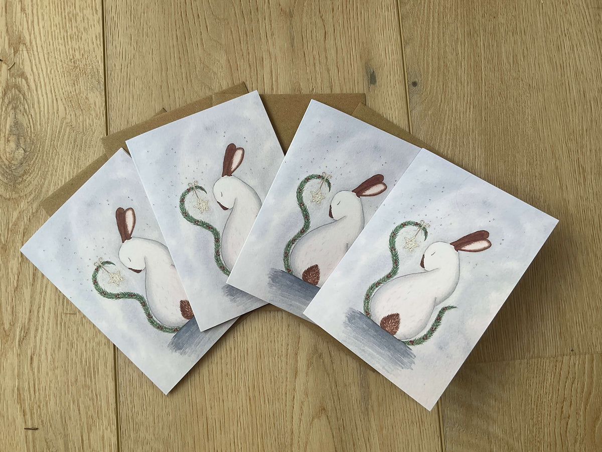 A pack of four luxury Christmas greeting cards printed in the UK featuring the whimsical My Christmas Star white rabbit artwork against a frosty blue background