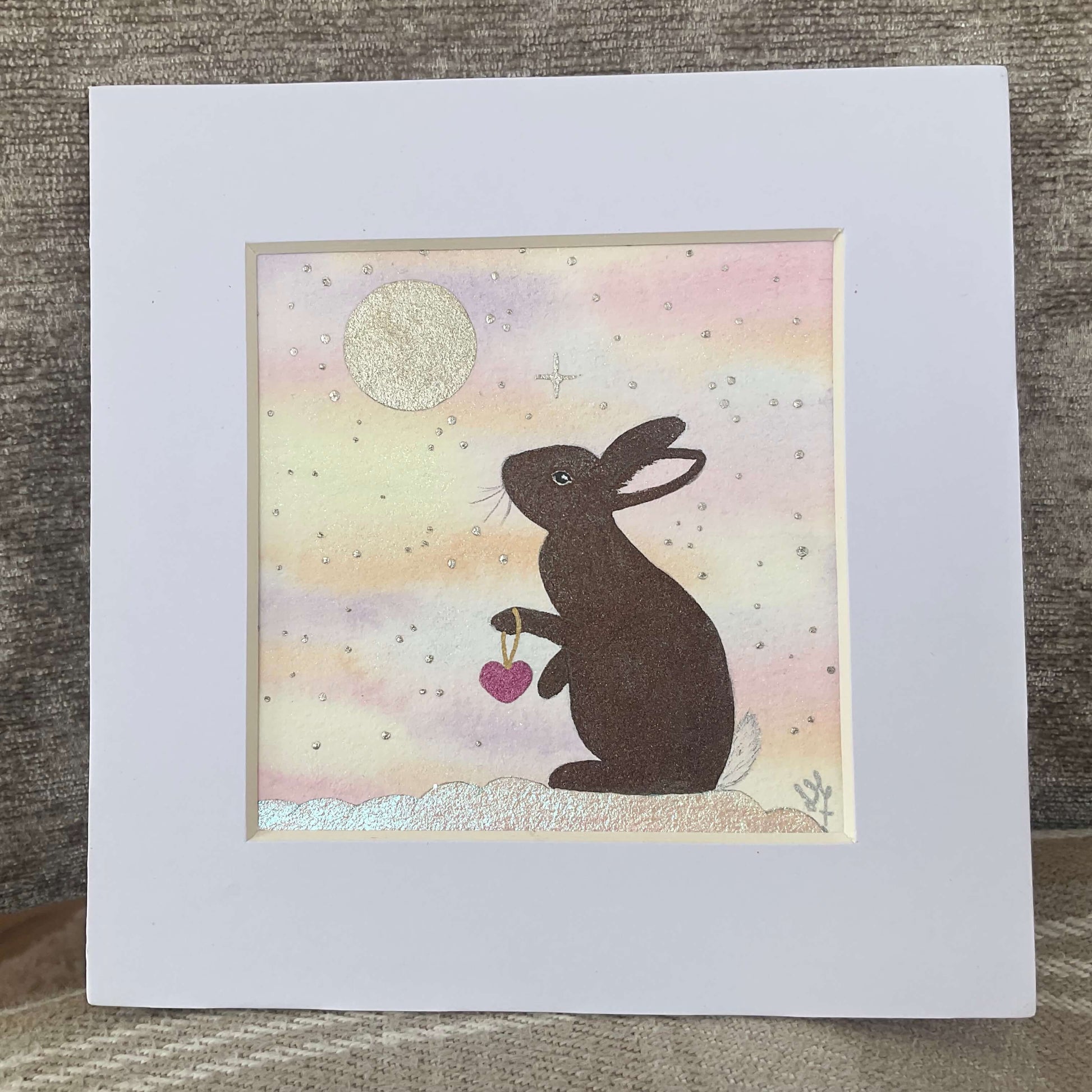 Original brown bunny art print titled A Love Kept in the Stars featuring a whimsical watercolor rabbit stargazing under a midnight blue sky with gold stars