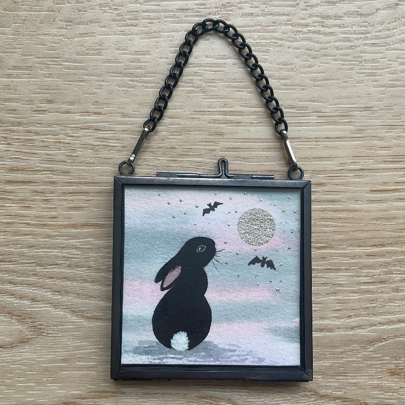 Original mini watercolor painting titled Under the Silver Moon featuring a black rabbit silhouette looking up at a silver metallic moon and bats